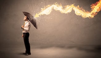 Business man defending himself from a fire arrow with an umbrella on grungy background