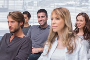 Patients listening in group therapy with one man smiling at the camera in office