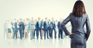 Powerful businesswoman standing with back with business team at background