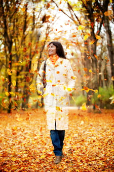 Autumn woman walking outdoors and leaves falling on her