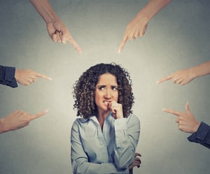 Concept of social accusation of guilty businesswoman many fingers pointing at isolated on grey office wall background. Portrait scared anxious embarrassed woman biting fingernails-1