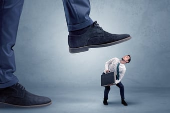 Young small businessman is trampled by a big foot in an empty space